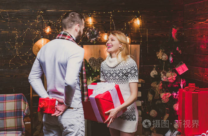 快乐的女人和男人互相赠送圣诞礼物.相爱的圣诞夫妇.可爱幸福的一对.