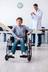 年轻男医生儿科医生和坐轮椅的男孩