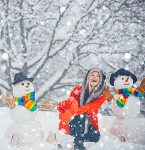 有趣的雪人。圣诞快乐，节日快乐。圣诞准备有趣的女孩堆雪人。雪人和风趣女孩在雪地里。雪地女孩。