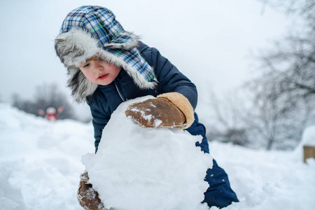 寒冬公园里的冬天的孩子们雪地花园里小男孩的肖像画在堆大雪球照片