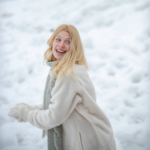 戴手套的女孩抱着雪球。冬天快乐女人的画像。户外快乐的女孩。快乐的女人手里拿着雪球。