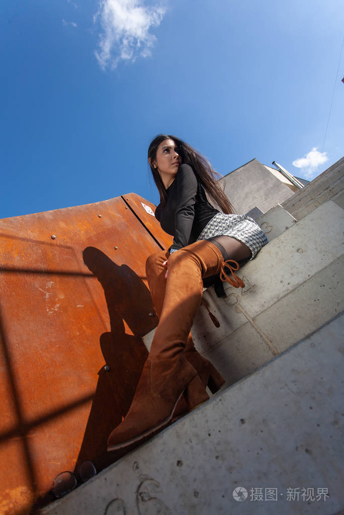 时髦的女模特坐在大楼的台阶上摆姿势