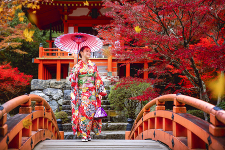 穿着和服的日本女孩走在红桥上