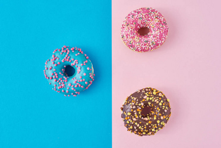 粉彩和蓝色背景的甜甜圈。极简创意食物构成。平铺式
