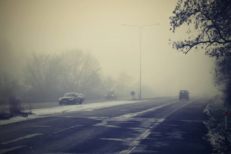 雾中的汽车。冬季恶劣的天气和路上危险的汽车交通。雾中的车辆。