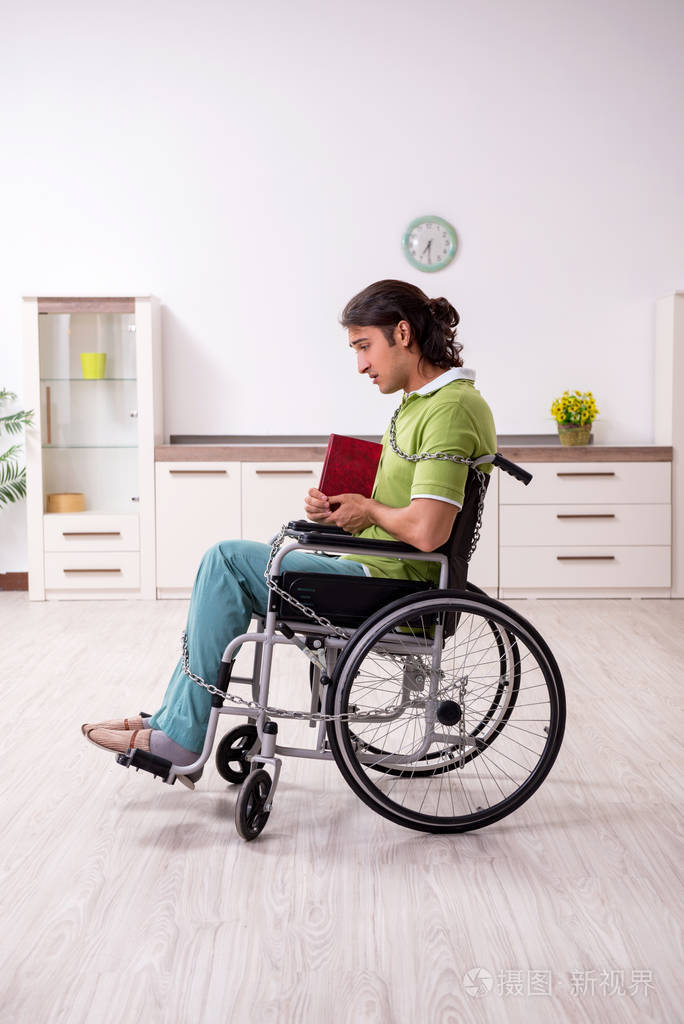 年轻男性残疾人在轮椅上受苦在家