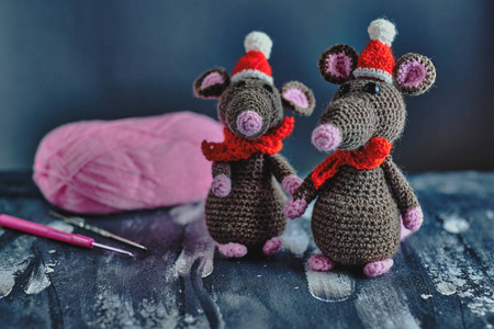 可爱的手工制作的阿米古鲁米老鼠，戴着圣诞帽和红领巾，站在蓝色背景上明亮的纱线线旁。2020年新概念