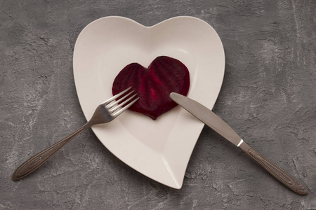 Plate with red heart and fork on concrete table. Valentines Day 