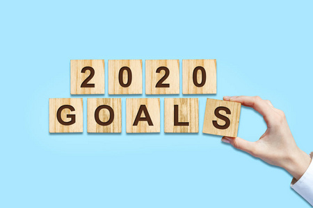 2020目标。女性用木块拼字。被隔离在蓝色背景下。新年目标概念。
