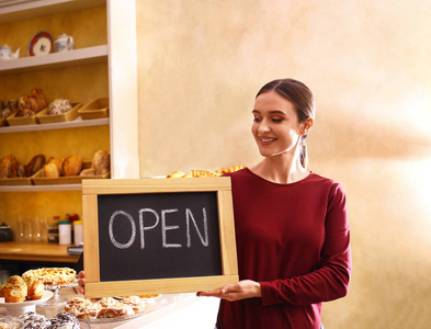 女店主手握面包店招牌图片