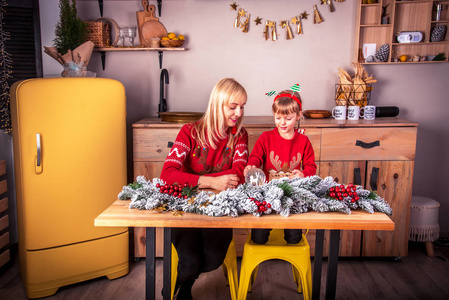 Young attractive smiling woman with her daughter in the kitchen 