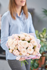 女人手中的单束灌木玫瑰。欧洲花店。花店里花匠的工作。送鲜切花。