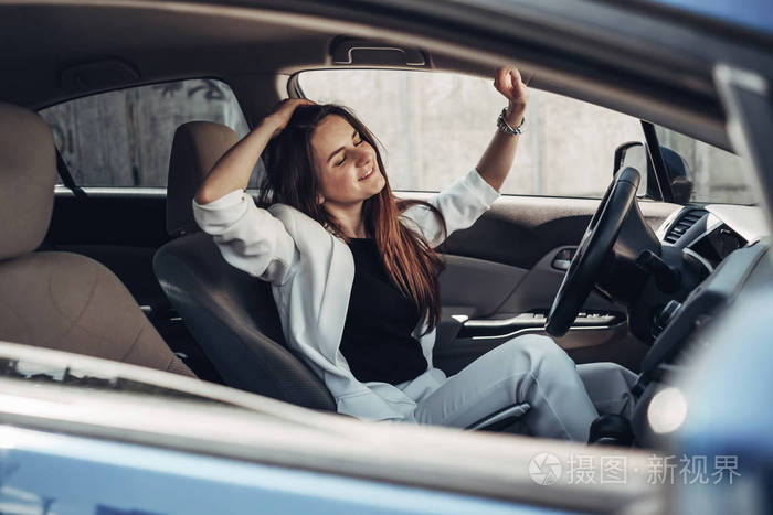 时尚时尚的司机女孩穿着白色西装坐在车里