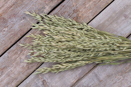木质背景上的一捆燕麦穗.照片