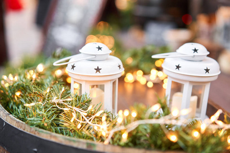 在欧洲小城老城的圣诞集市上，发光的烛光灯笼和圣诞装饰品摆在桌上。灯泡花环