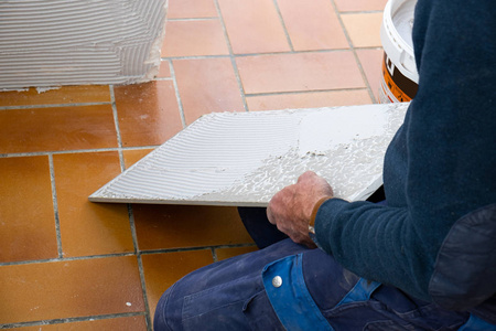 铺瓷砖的人在铺瓷砖之前先把胶水涂在瓷砖上