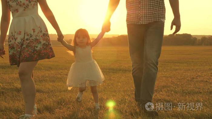 孩子和爸爸妈妈在夕阳下玩耍.和一个小孩子在大自然中散步.