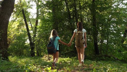 疲惫的女孩背着背包穿过森林的灌木丛。女徒步旅行者在森林里散步。快乐的夏日公园徒步女孩。少女度假冒险。