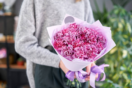 女士手中的紫罗兰色单束康乃馨。欧洲花店。花店里花匠的工作。送鲜切花。