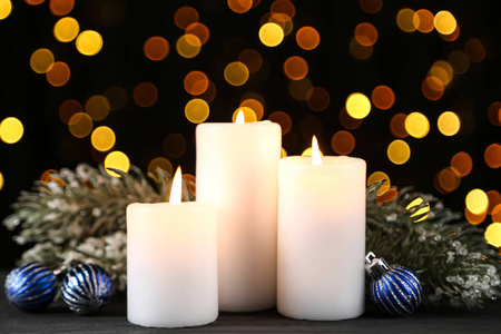 Christmas candles with baubles and fir tree branches on blurred 