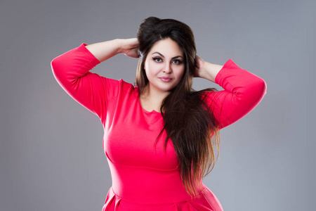 穿着红色连衣裙的快乐大码模特,灰色背景下长发的性感胖女人,身材积极