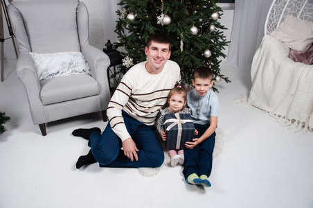 爸爸带着孩子，漂亮的女孩和一个可爱的男孩在圣诞树旁