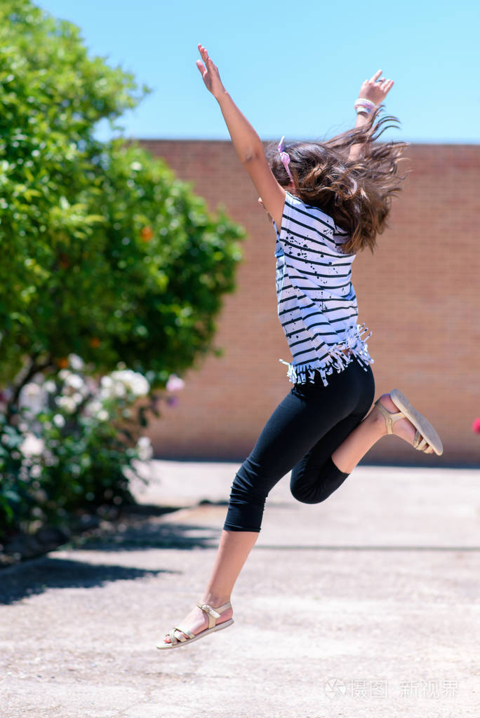 阳光明媚的一天快乐的女孩从街上的台阶上跳下来