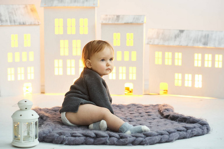 一个小孩坐在一张灰色的地毯上，背景是玩具狗