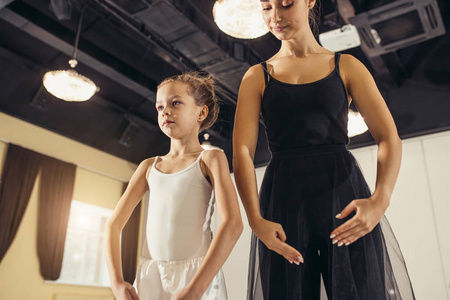 在芭蕾舞工作室训练小女孩的年轻芭蕾舞女演员