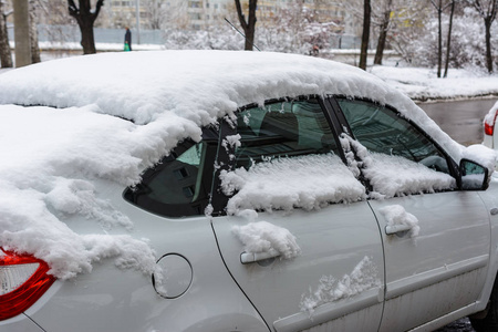 汽车上覆盖着新的白雪，汽车被雪覆盖了一个障碍