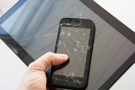 那家伙手里拿着一部显示器坏了的黑色智能手机.现代小玩意的破屏.