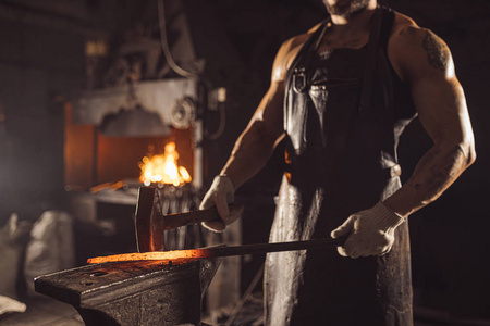 留着胡子的白人年轻人用锤子打铁照片