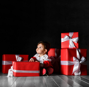 穿着圣诞老人服装的小宝贝，深色背景上有红色的盒子