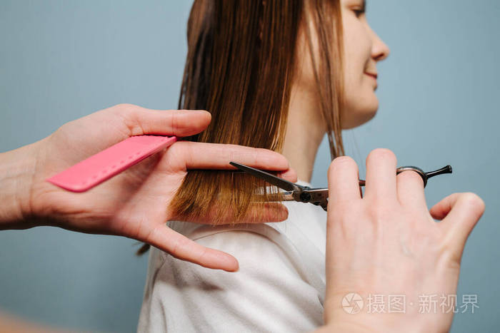 女理发师用手在蓝色背景上修剪客户的头发