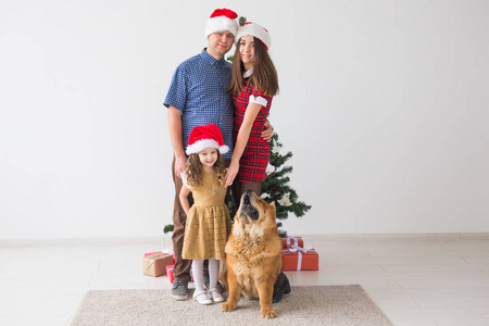 宠物，节日和节日概念一家人和狗站在圣诞树附近。