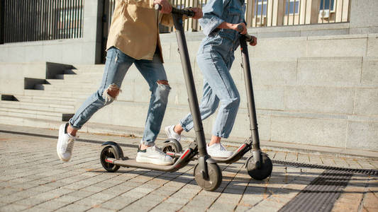 让我们骑吧。阳光明媚的日子里，男孩和女孩开着电动滑板车玩得很开心