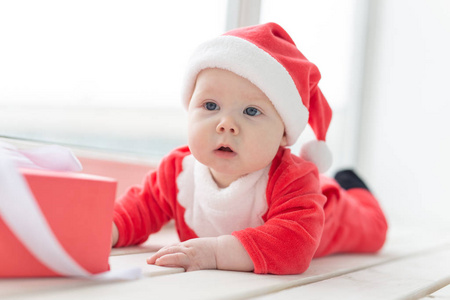 美丽的小宝宝庆祝圣诞节。新年假期。一个穿着圣诞服装戴着圣诞帽的婴儿