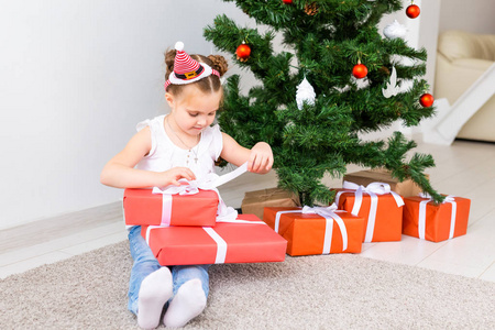 孩子打开圣诞礼物。孩子在圣诞树下拿着礼品盒。