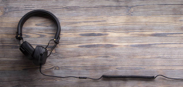 木质背景的现代耳机，长电缆，仅限音乐