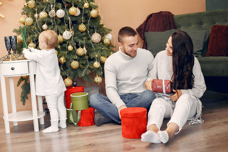 一家人坐在家里靠近圣诞树