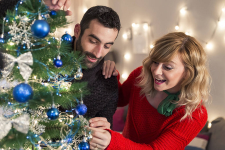 一对夫妇在客厅装饰圣诞树。假期准备。