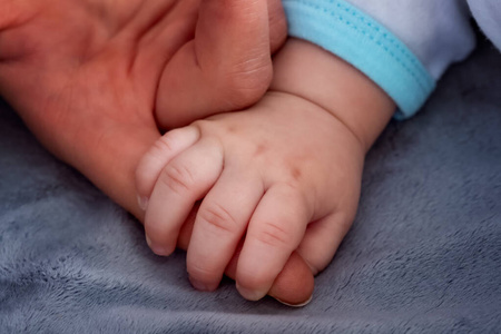 Baby hand holding mothers finger 