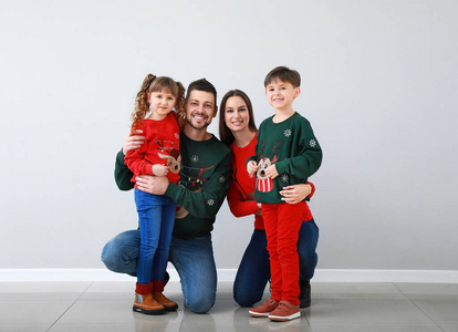 幸福的一家人穿着圣诞服装在灯墙附近