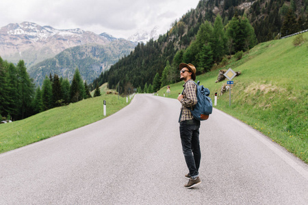 兴奋探索一个戴着帽子和黑色牛仔裤的时髦年轻人在早晨欣赏美丽的