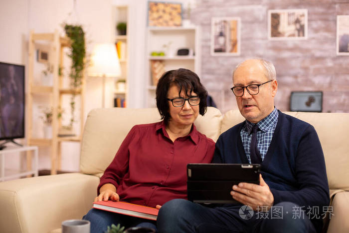 一对漂亮的老夫妇用数字平板电脑和家人聊天