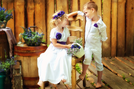 穿着白色衣服的小男孩和女孩穿着乡村风格的装饰品。生态家庭。儿童时期的有机生态生活方式。兄弟姐妹互相看。夏季