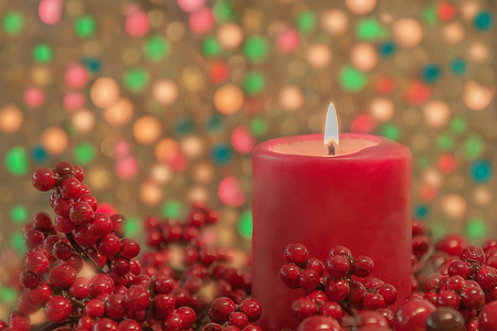 圣诞蜡烛和红莓装饰在五彩缤纷的背景和灯光