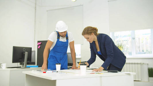 Engineer stands next to woman, who draw on whatman paper with pe