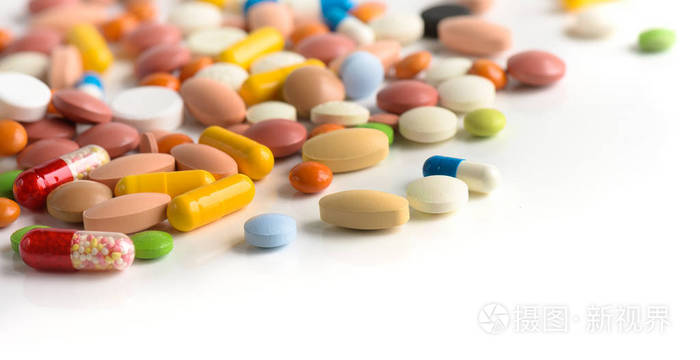 白色的桌子背景上有很多不同颜色的药丸药片胶囊药丸