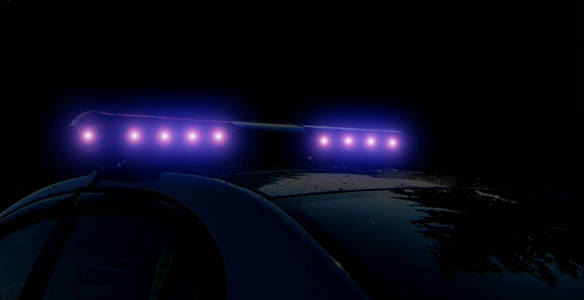 夜幕下城市街道上警用报警警车模糊的散焦轮廓。夜色中闪烁的蓝色警车led灯。
